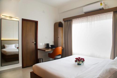 a hotel room with a bed with a vase of flowers on it at Hunkal Stays in Chikmagalūr
