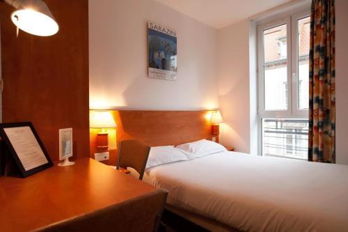 a hotel room with a bed and a desk and window at Hotel Le 21ème in Strasbourg