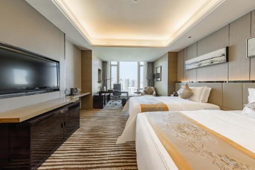 a hotel room with two beds and a flat screen tv at Shenzhen LANGYUE International Hotel in Longgang