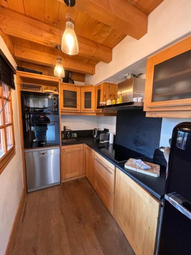 une cuisine avec des placards en bois et des comptoirs noirs dans l'établissement Appartement duplex megeve, à Megève