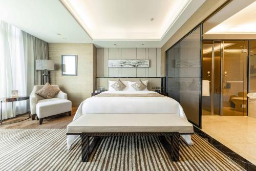 a large bedroom with a large bed and a chair at Shenzhen LANGYUE International Hotel in Longgang