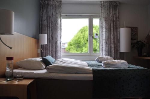 a bed in a bedroom with a window at Scandic Östersund Syd in Östersund