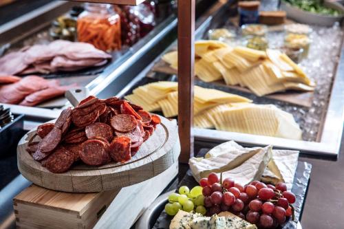 a table with a bunch of meats and grapes and cheese at Scandic Östersund Syd in Östersund