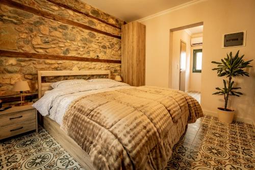 a bedroom with a bed and a stone wall at Σοχός Παραδοσιακές Οικίες- ΒΕΝΙΖΕΛΟΥ in Zokhós