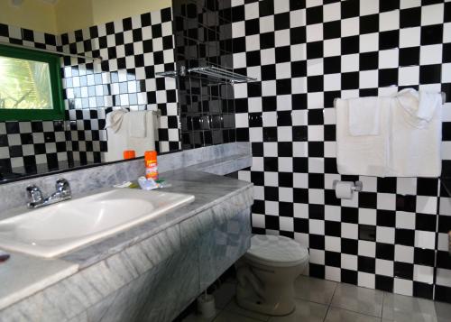a bathroom with a sink and a checkered wall at Hosteria Canoa in Canoa