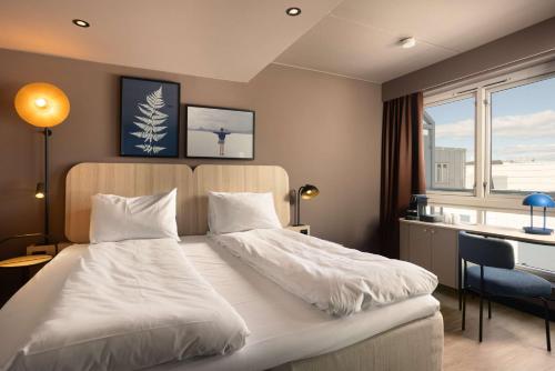a bedroom with a white bed with a desk and a window at Scandic Victoria Oslo in Oslo