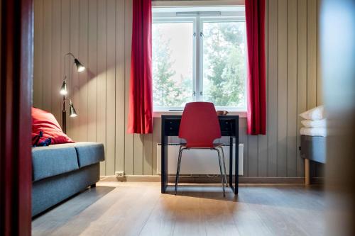 a red chair sitting at a desk in a room with a window at Scandic Karasjok in Karasjok