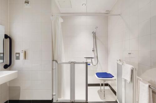 Ramada by Wyndham Cobham في كوبهام: حمام أبيض مع دش ومغسلة
