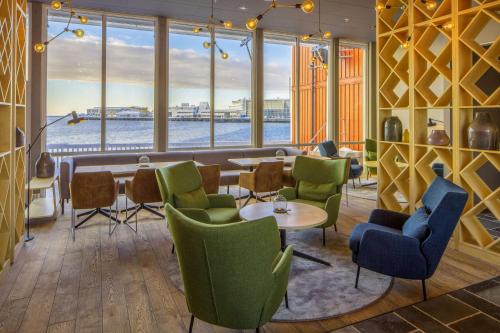 a lobby with tables and chairs and a large window at Scandic Svolvær in Svolvær