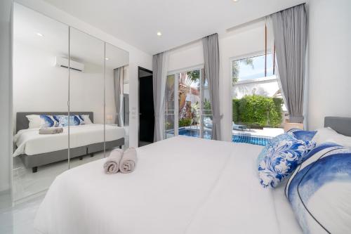 a white bedroom with two beds and a mirror at The Greens Phuket Villa with swimming pool 18 in Ban Saiyuan (1)