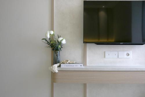 a vase of flowers on a counter with a tv at Japandi Style One-Bedroom Apartment Gold Coast PIK in Jakarta