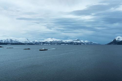 a boat in a large body of water with snow covered mountains at Scandic Seilet Hotel in Molde