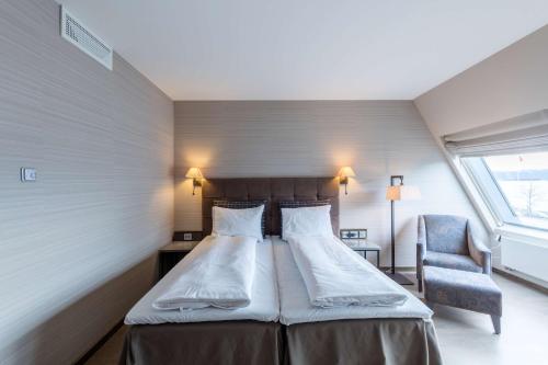a bedroom with a bed and a chair and a window at Scandic Seilet Hotel in Molde