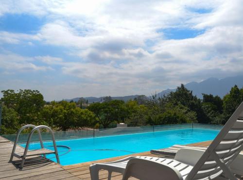 a swimming pool with two lawn chairs and a deck at 4 Piet Retief in Stellenbosch
