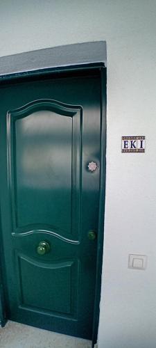 una porta verde con un cartello su un muro di Eki a Conil de la Frontera