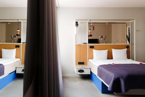 a hotel room with two beds and a mirror at Scandic No 53 in Stockholm