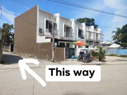 a building with a sign that reads this way at R & J Homestay in Naga Cebu in Tina-an