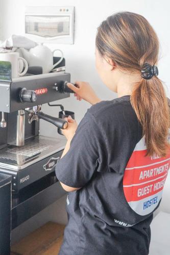 a young woman is using a coffee machine at Margarita Surf Hostel Canggu in Canggu