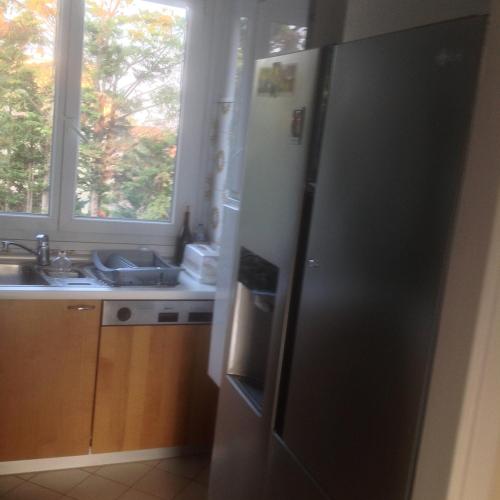 Il comprend une cuisine équipée d'un réfrigérateur, d'un évier et d'une fenêtre. dans l'établissement Appartement lumineux à 20mn de Paris en RER A, à Maisons-Laffitte