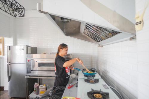 a woman in a kitchen preparing food in a bowl at Margarita Surf Hostel Canggu in Canggu