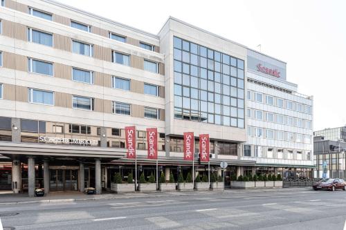 a large building with red banners in front of a street at Scandic Mikkeli in Mikkeli
