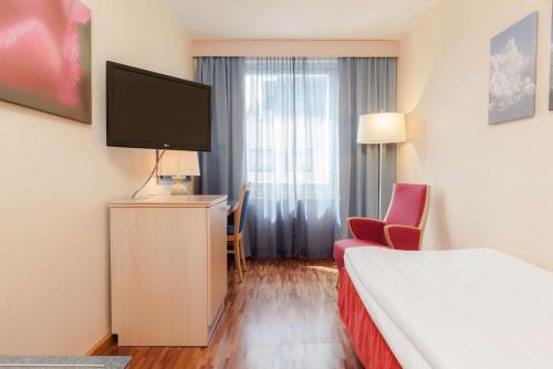 a hotel room with a bed and a flat screen tv at Scandic Mikkeli in Mikkeli