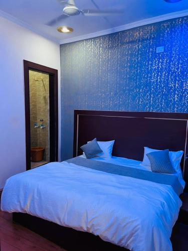 a bedroom with a large bed with a blue wall at Shri Gauraj Dham in Chhatikara