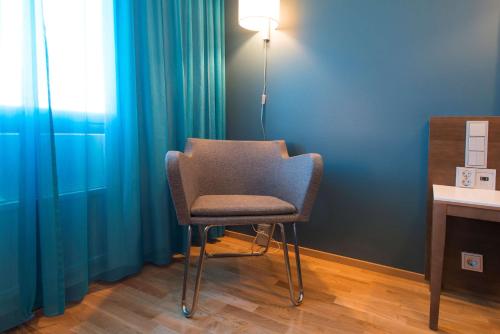 a chair sitting in a room with blue curtains at Scandic Oulu Station in Oulu