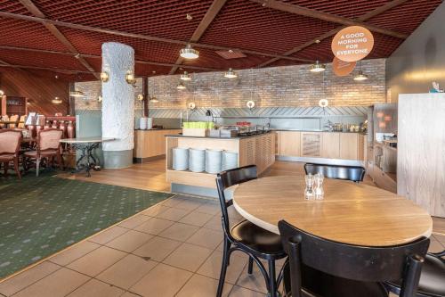 a restaurant with a wooden table and chairs at Scandic Oulu Station in Oulu