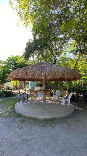 a large straw umbrella with chairs and a table at ELEN INN - Malapascua Island Air-conditioned Room1 in Malapascua Island
