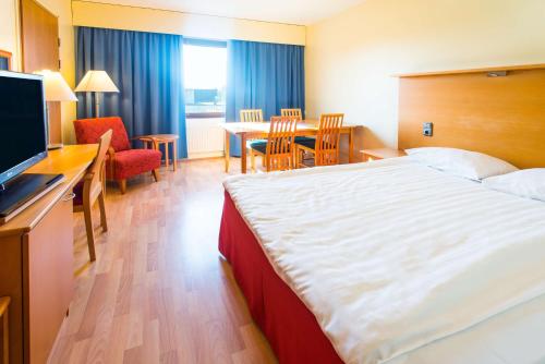 a hotel room with a large bed and a table at Scandic Kemi in Kemi