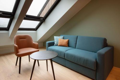 a living room with a blue couch and a chair at Scandic Voss in Vossevangen