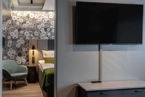 a room with a bed and a television on a wall at Scandic Pasila in Helsinki