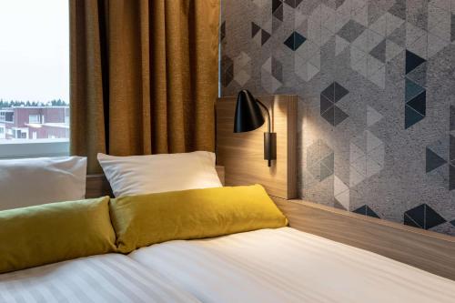 a bed with a yellow pillow on top of it at Scandic Pasila in Helsinki