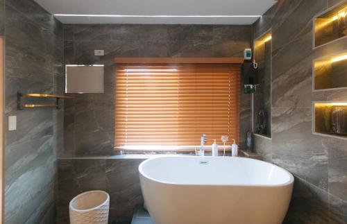 a bathroom with a large tub and a window at Movietelle by RedDoorz in Lapu Lapu City