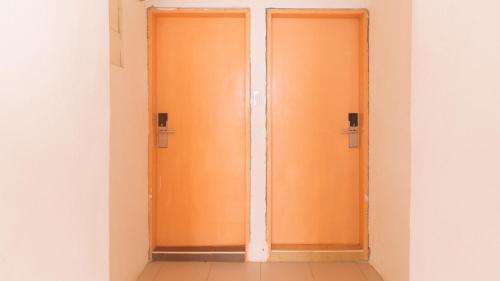 two orange elevator doors in a white room at Movietelle by RedDoorz in Lapu Lapu City