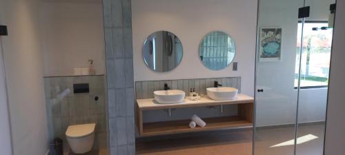 a bathroom with two sinks and two mirrors at The Whale's Tale Guesthouse in Hermanus