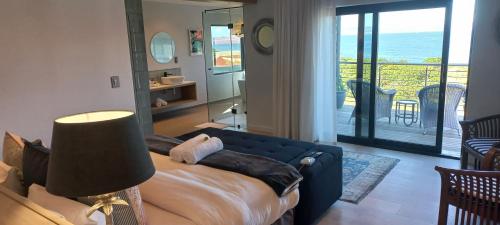 a living room with a blue couch and a balcony at The Whale's Tale Guesthouse in Hermanus