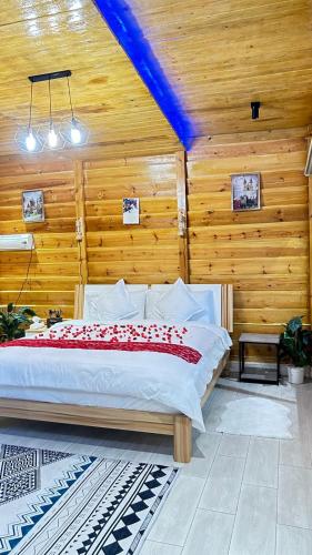 a bedroom with a large bed in a room with wooden walls at كوخ الوهط الريفي in Taif