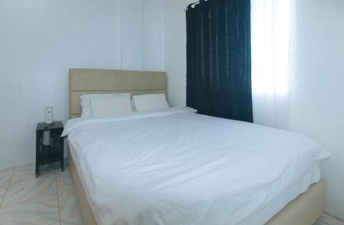 a bedroom with a bed with white sheets and a window at Movietelle by RedDoorz in Lapu Lapu City
