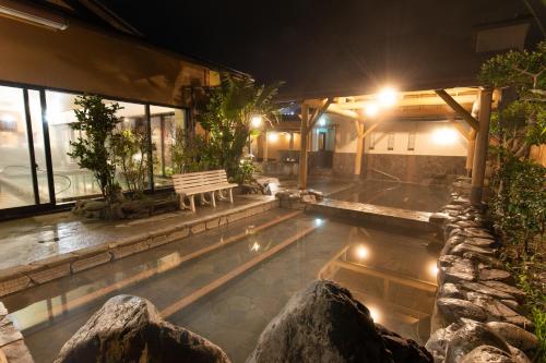 a pool with a bench next to a building at night at Ibusuki Kokoronoyado in Ibusuki