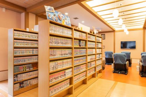 a library with shelves of books and chairs at Ibusuki Kokoronoyado in Ibusuki
