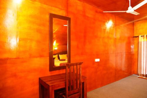 a mirror and a chair in a room at Golden Beach Hotel & Restaurant in Trincomalee