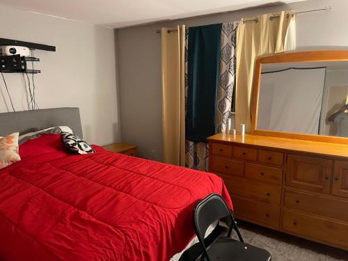 a bedroom with a red bed and a dresser with a mirror at Dayton get away in Dayton