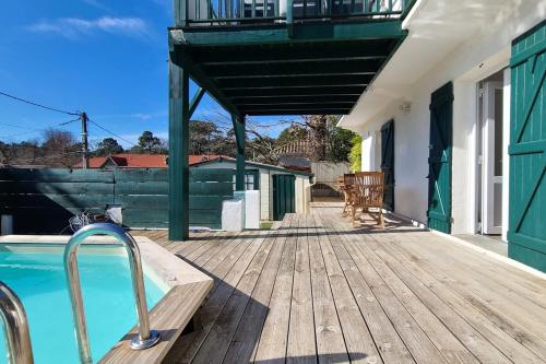 une terrasse en bois avec une piscine dans une maison dans l'établissement Spacious house with beautiful garden, à Arcachon