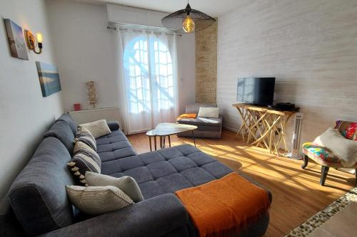 un salon avec un canapé bleu et une télévision dans l'établissement Spacious house with beautiful garden, à Arcachon