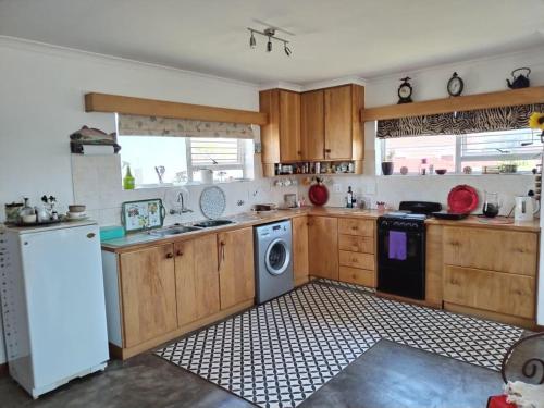a kitchen with wooden cabinets and a washing machine at 120 steps to the beach in Pringle Bay
