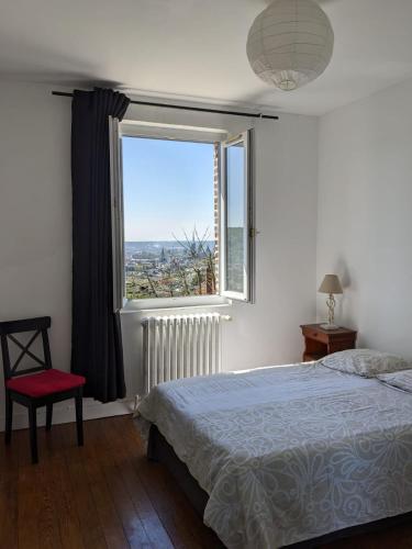 une chambre avec un lit et une grande fenêtre dans l'établissement House with garden and view of Rouen, à Rouen