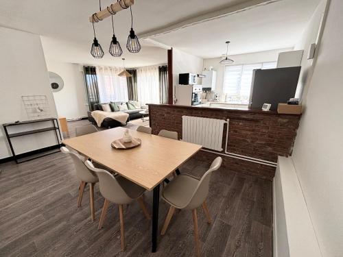 Il dispose d'une cuisine et d'un salon avec une table et des chaises en bois. dans l'établissement Appartement spacieux et lumineux, 3 chambres à Coudekerque-branche, à Coudekerque-Branche