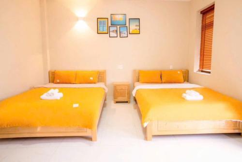 two beds in a room with orange sheets at Merci Đà Lạt Home in Da Thanh
